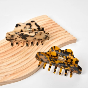Macro detail of tortoiseshell acetate hair claws with cloud edges on a wooden tray