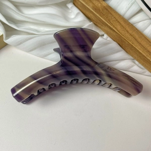 Détail de la pince à cheveux en acétate à rayures violettes avec logo de marque gravé