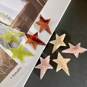 Detailed view of acetate star hair clips with marble texture and metal duckbill grip