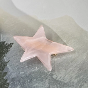 Detailed macro view of a pink marble acetate star hair clip with a golden metal duckbill base