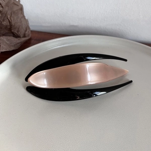 Detail view of the sleek acetate hair clip featuring a modern pink and black layered design