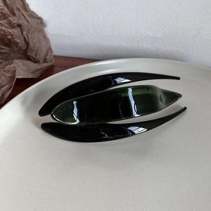 Detailed view of a green acetate hair claw clip on a minimalist beige display plate
