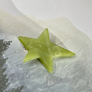 Macro view of green acetate star hair clip with white marble texture on scenery card