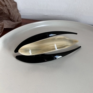 Detailed view of large acetate hair claw with beige marble pattern on ceramic plate