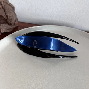 Detail view of a sleek acetate hair claw clip with dark blue and black streamlined design