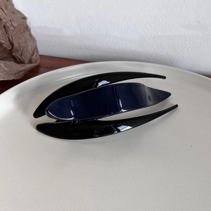 Detail of minimalist curved cellulose hair clip in deep blue and black with high gloss finish