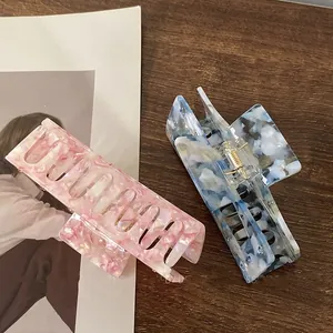 Detailed view of pink and blue acetate hair claws with marble texture on wooden surface