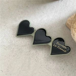 Dettaglio di un fermaglio per capelli a cuore nero ondulato con scritte dorate