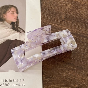 Detail of lavender marble acetate hair claw clip with rhinestones on a wooden surface