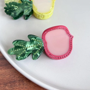 Dettaglio della molletta per capelli a forma di ravanello rosa con strass lucidi