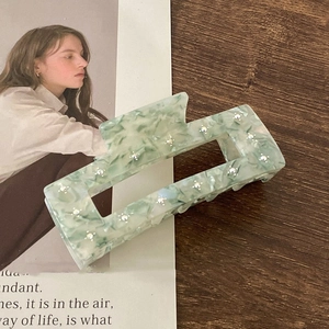 Detail of a light green marbled acetate hair claw clip featuring elegant inlaid rhinestones
