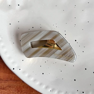 Detailed shot of rectangle acetate hair claw with gold metal clip and stripe pattern