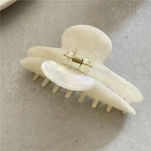 Détail d'une pince à cheveux en acétate blanc perle avec un ressort en métal doré durable