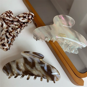 Trois pinces à cheveux en acétate motifs léopard, blanc perlé et marbre sur fond blanc
