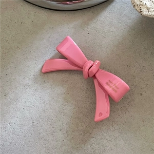 Gros plan détaillé d'une pince à cheveux rose en acétate avec texte doré fait à la main