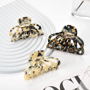 Three acetate hair claws with tortoiseshell and marble patterns on white stone plate