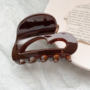 Macro detail of dark brown heart-shaped acetate claw clip with polished glossy finish