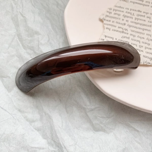 Detailed close-up of dark brown heart-shaped acetate claw clip with a glossy finish