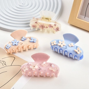 Detailed view of acetic floral hair claws with rhinestones in pastel cream colors