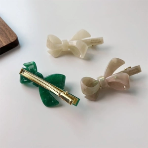 Three acetate bow hair clips in cream, green and pink with marble texture and gold base