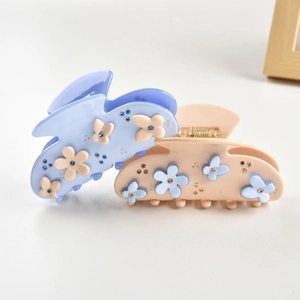 Detail of elegant acetate flower hair claws with rhinestones in purple and beige tones