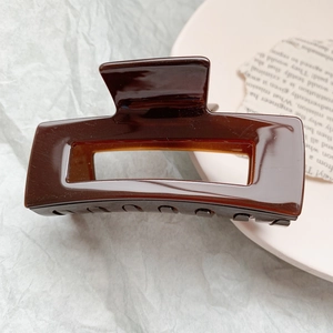 Detailed close-up of a large amber brown acetic acid hair claw clip on a textured background