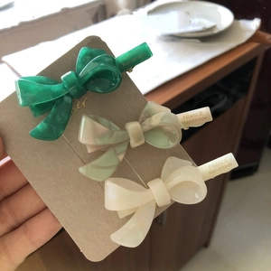 Detailed macro view of three acetate marble hair clips with golden metal duckbill grips