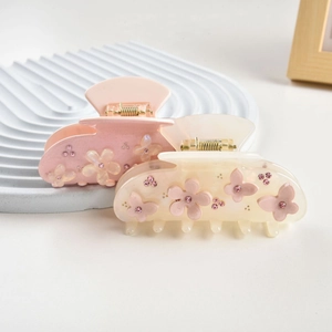Detailed view of floral hair claws with pink butterfly accents and sparkling rhinestones