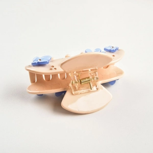 Detailed side view of a pink acetate hair claw clip featuring blue rhinestone flowers