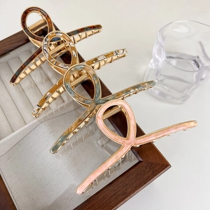 Close-up of four acetate hair claws in tortoise, amber, and marble patterns on metal clips