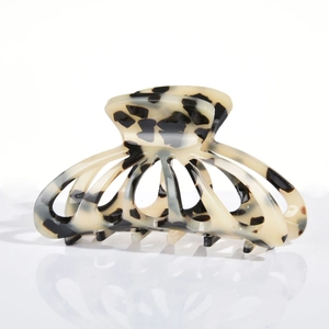 Detail of cream acetate hair claw clip with vintage tortoiseshell pattern on white background