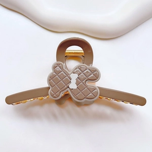 Detailed view of a brown bear claw clip featuring a quilted pattern and white bow accent