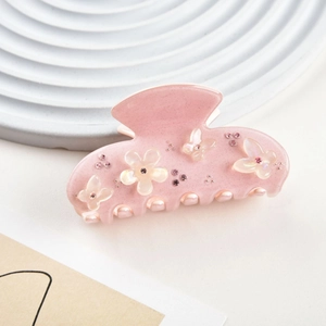 Detail of a pink glitter hair claw clip with crystal flowers and butterflies