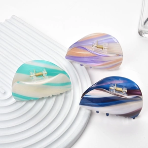 Three acetate hair claws with marble texture patterns and gold metal springs on white background