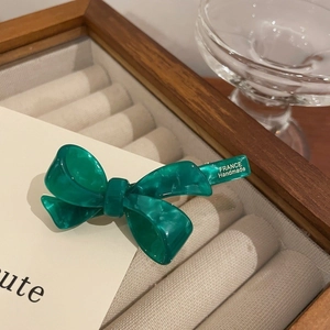 Detailed macro view of a green marbled acetate bow hair clip with gold France handmade text
