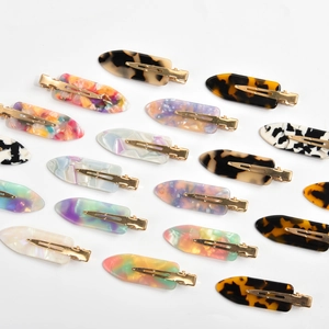 Macro detail of various colorful acetate hair clips with golden metal duckbill base