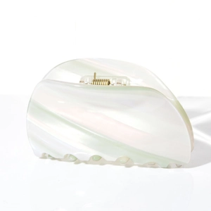 Detail of acetate claw clip featuring iridescent striped texture and golden metal spring