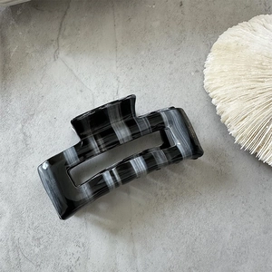 Detailed close-up of handmade acetate hair claw with chic black and white marble texture