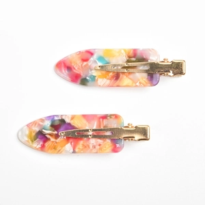 Detail view of colorful marble texture acetate hair clips with gold metal duckbill jaws