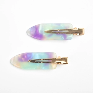 Close-up of duckbill hair clips with purple and blue marble pattern resin and gold metal base