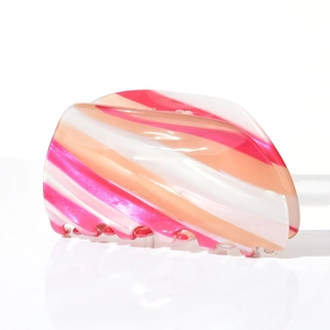 Close-up of large acetate hair claw clip with pink and white stripes on glossy surface
