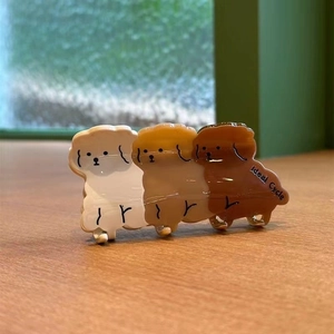 Détail de trois pinces à cheveux chiot en acétate, couleurs blanc, kaki et marron