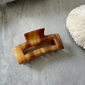Detailed macro view of the rectangular amber acetate hair claw with marbled patterns