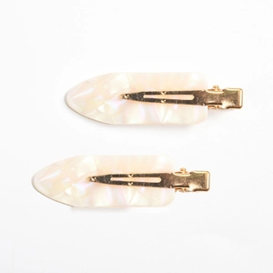 Detail of two cream marble acetate duckbill hair clips with gold metal base