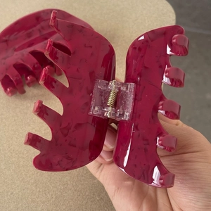Detail of large acetate shark hair claw clip with dark red marble texture and spring