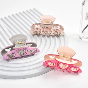 Trois pinces à cheveux en acétate avec design de cœur creux en rose, violet et beige