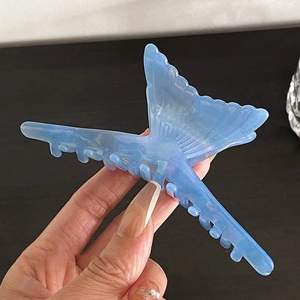 Détail de la pince à cheveux en acétate bleu en forme de queue de poisson