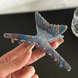 Détail d'une grande pince à cheveux en acétate avec texture marbrée bleue et dents antidérapantes