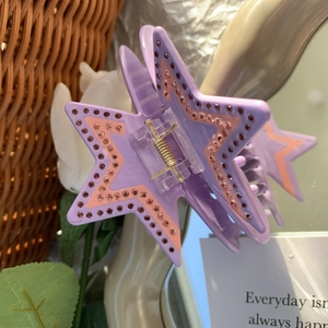 Gros plan sur une pince à cheveux étoile en acétate avec strass roses et base violette