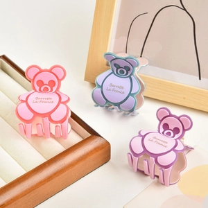 Vue détaillée de pinces à cheveux ours mignonnes en rose et violet sur plateau bois